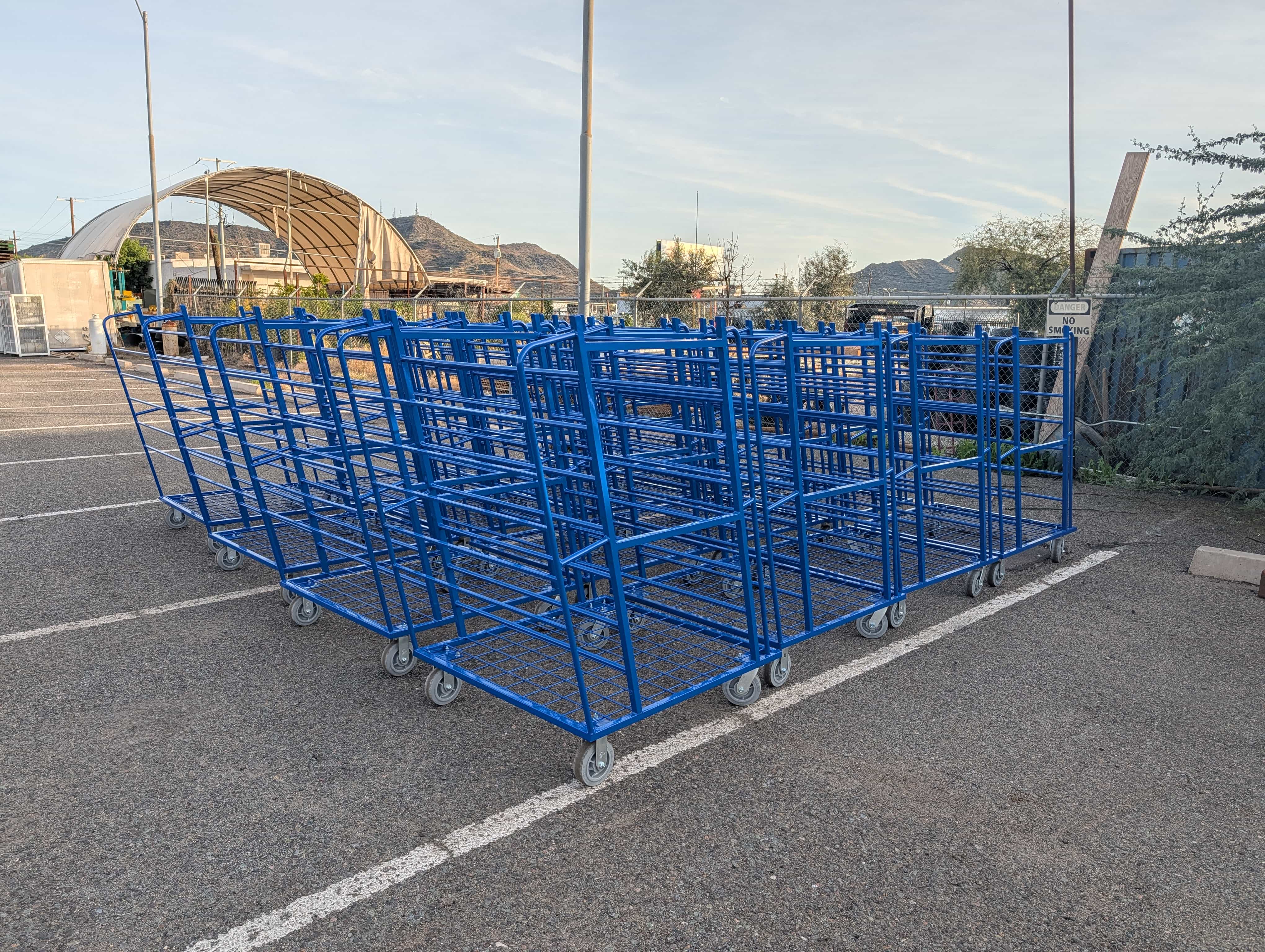 Custom blue rolling metal frames staged outside the fabrication shop