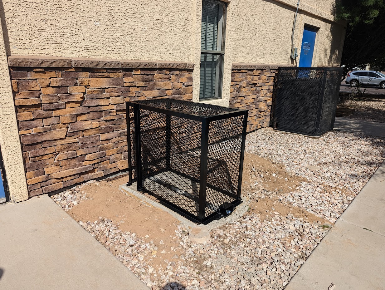 Black expanded metal HVAC security cage around a condenser